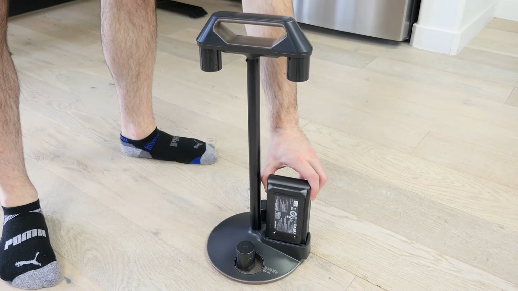 Osoba puni bateriju bežičnog usisivača na postolju za punjenje