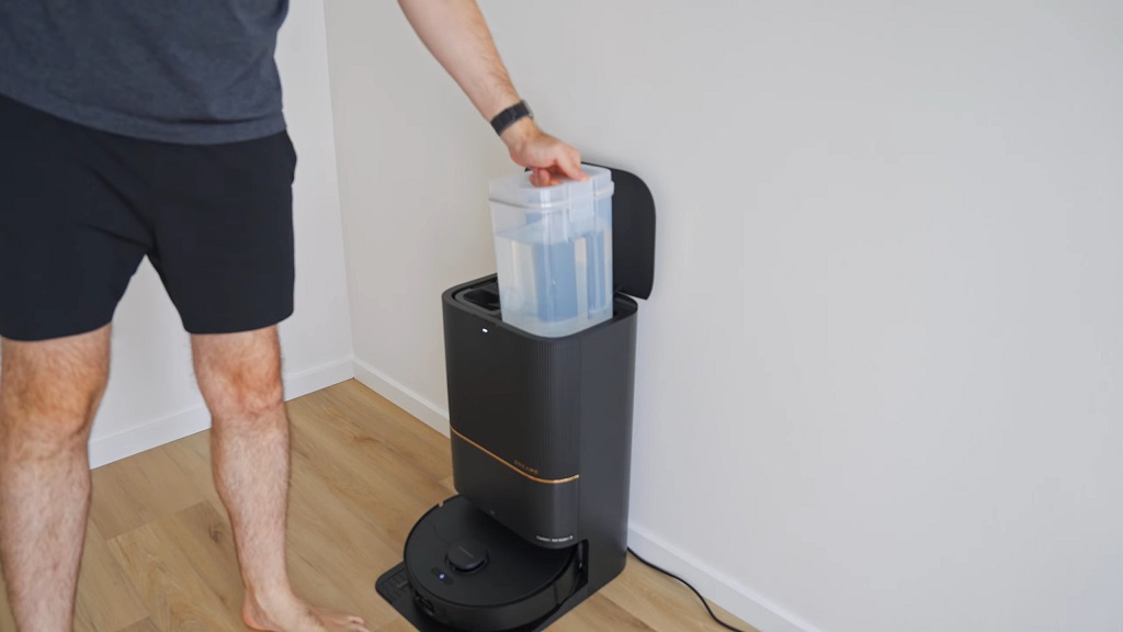 Osoba dopunjava stanicu za robot usisivač vodom tokom redovnog održavanja