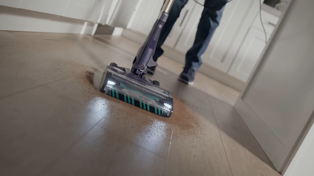 Osoba koristi žičani usisivač na drvenom podu za temeljno čišćenje prašine