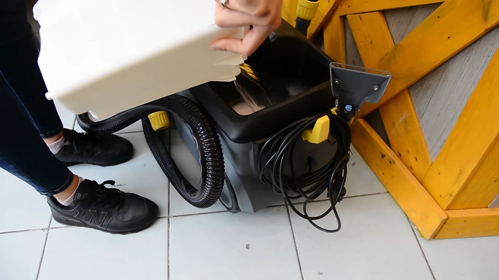 Osoba puni rezervoar usisivača za dubinsko pranje vodom i deterdžentom